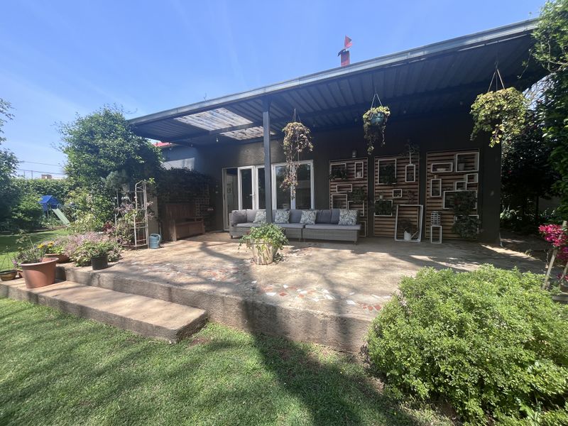 A covered outdoor patio area featuring concrete flooring, decorative wall paneling, and direct access to the home through sliding glass doors.