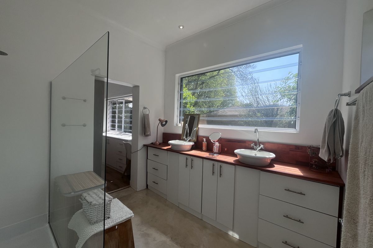 Modern bathroom featuring a double vanity with timber countertop, vessel sinks, and a large walk-in shower with a glass screen.