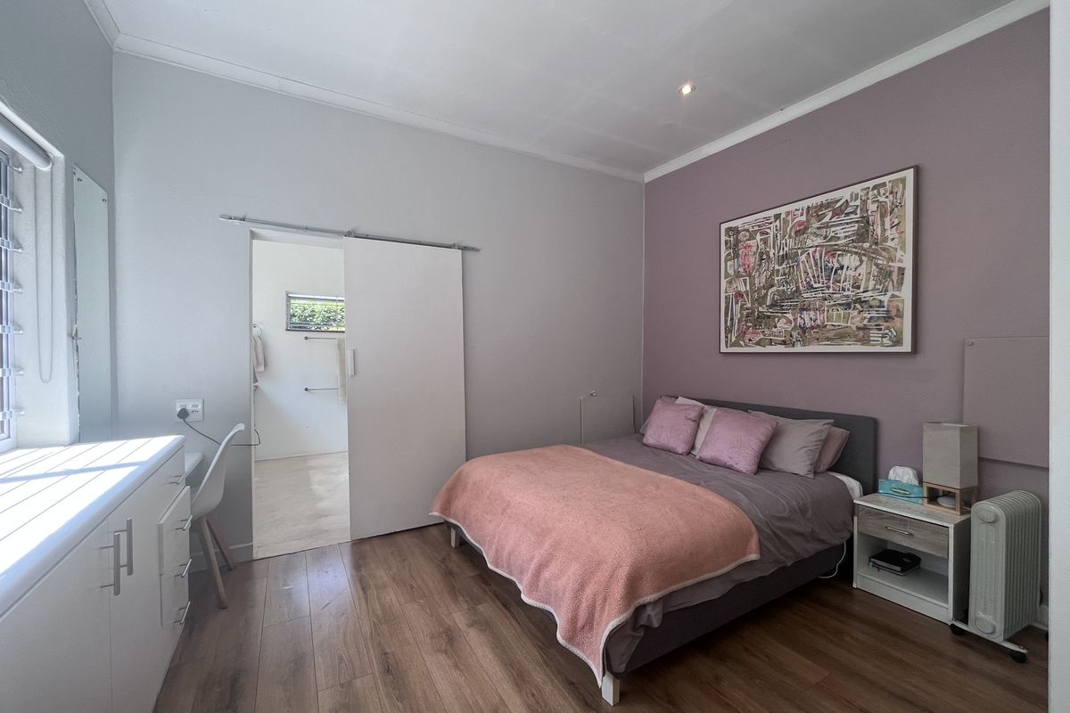A well-maintained bedroom featuring laminate flooring, built-in cabinetry, and a sliding door leading to an en-suite bathroom.