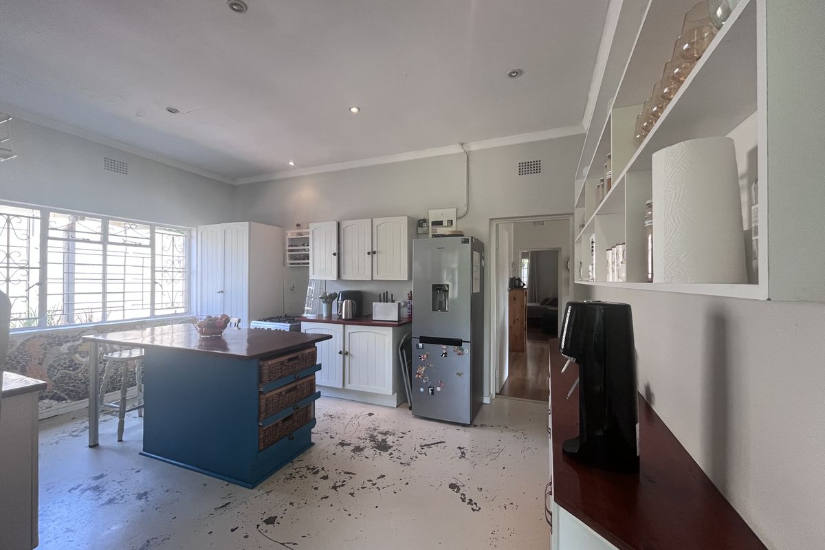 Kitchen featuring built-in cabinetry, a central island, and open shelving. The floor surface shows significant wear and requires refinishing.