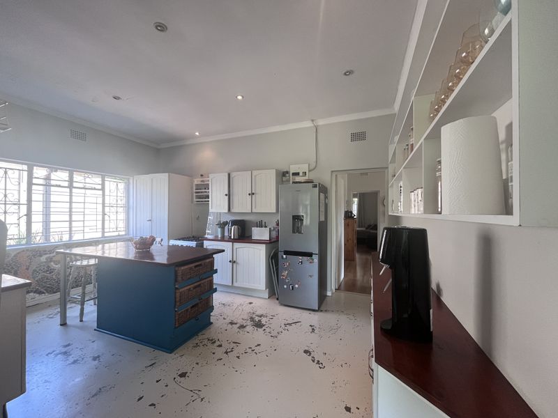 Kitchen featuring built-in cabinetry, a central island, and open shelving. The floor surface shows significant wear and requires refinishing.