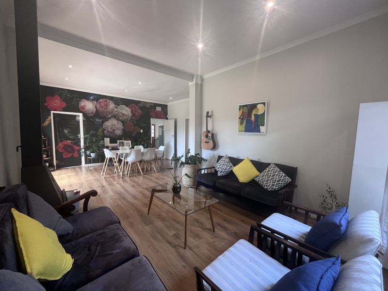 Spacious open-plan living and dining area featuring wood-look laminate flooring, recessed lighting, and a modern freestanding fireplace.