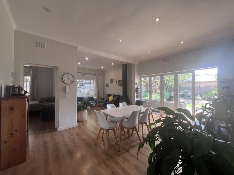 Spacious open-plan living and dining area featuring laminate flooring, a modern fireplace, and large stacking glass doors opening to the garden.