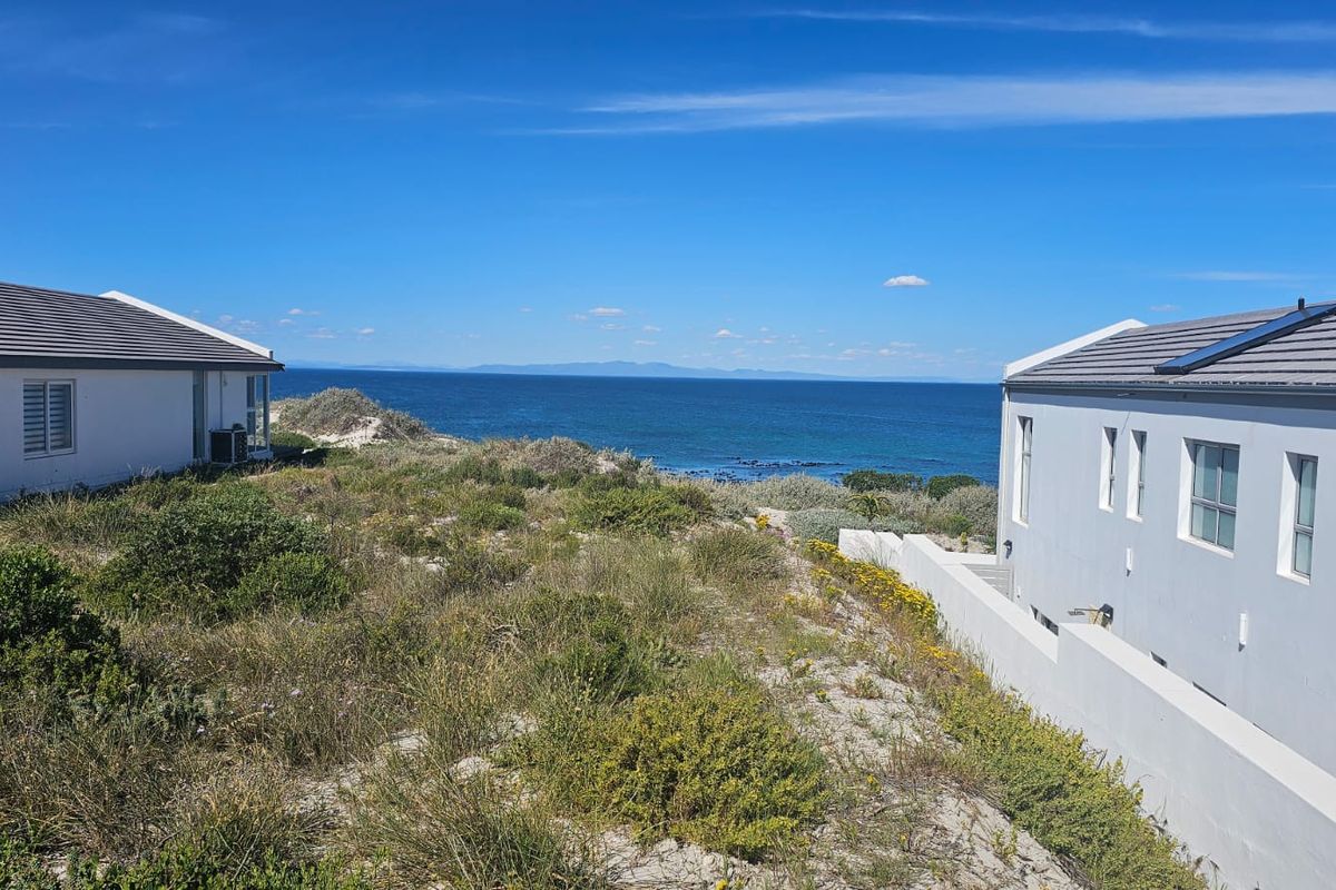 A scenic view of the ocean framed by two modern residential properties, showcasing the coastal landscape and natural surroundings.