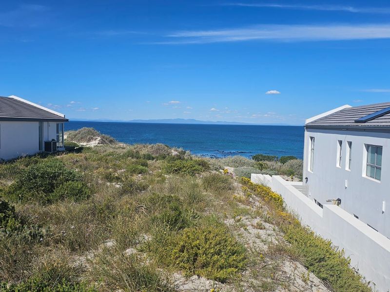 A scenic view of the ocean framed by two modern residential properties, showcasing the coastal landscape and natural surroundings.