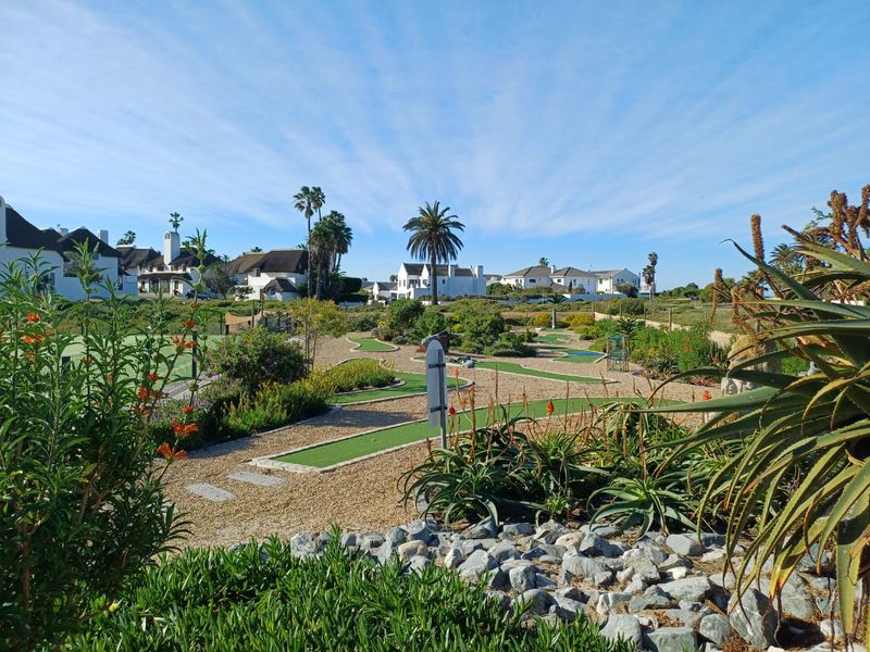 A well-maintained miniature golf course set within a landscaped residential estate garden, featuring manicured greens and native plantings.