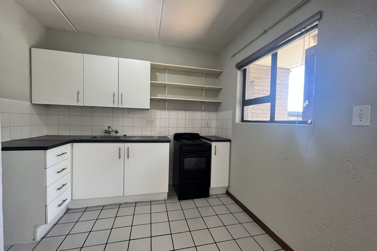 A functional kitchen featuring white cabinetry, tiled backsplash, open shelving, and a freestanding stove, offering a clean and practical layout.
