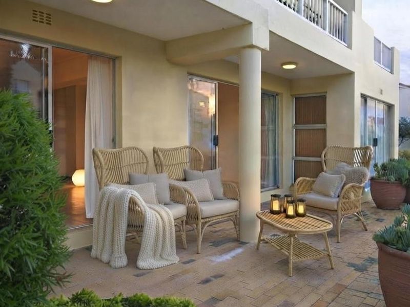 A covered ground-floor patio featuring brick paving, structural columns, and direct access to the interior through sliding glass doors.