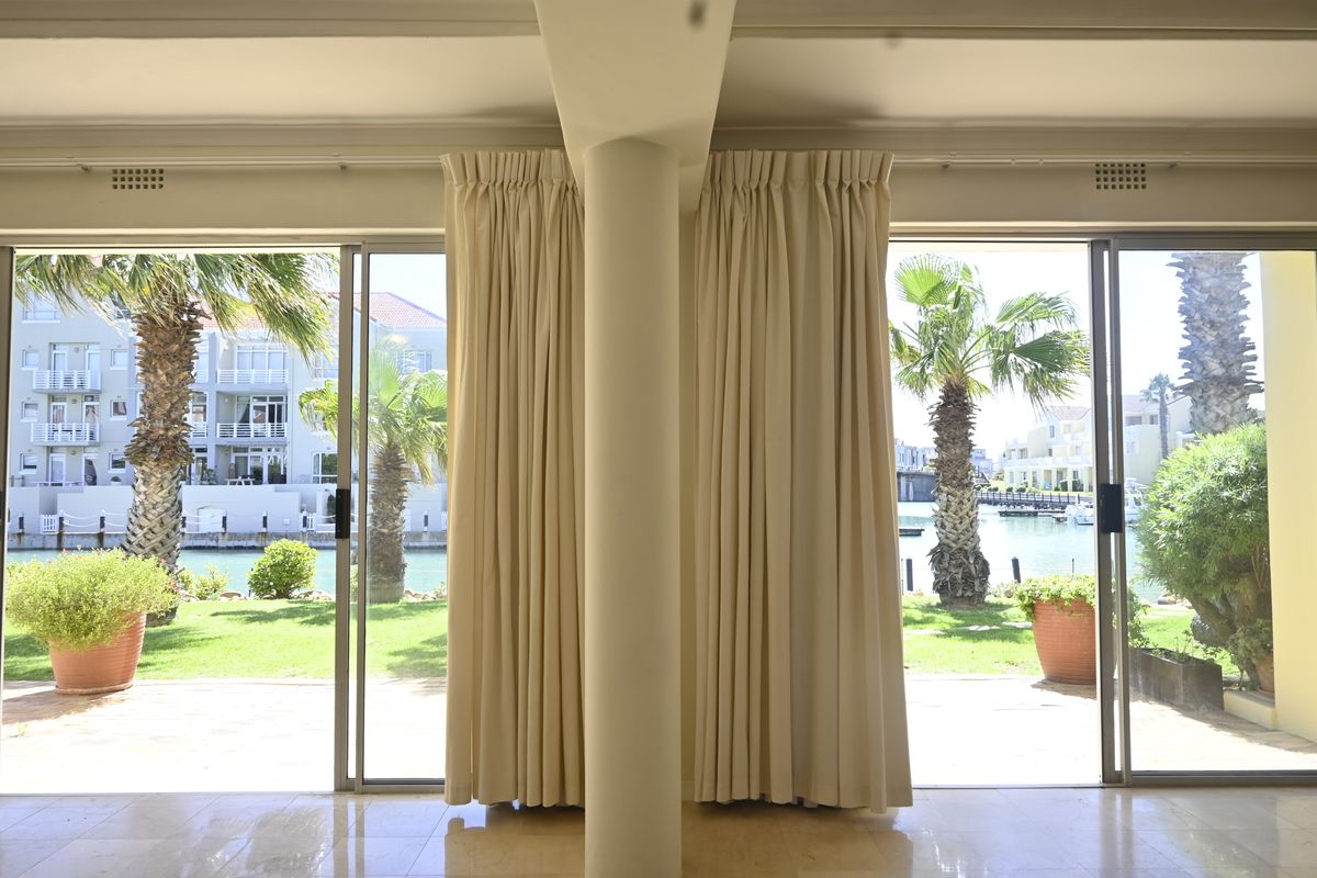 Bright living area featuring large sliding glass doors that open to a scenic waterfront view and garden.