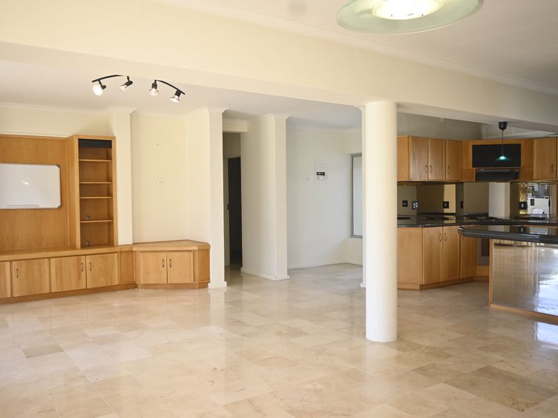 Spacious open-plan living and kitchen area featuring marble flooring, extensive built-in cabinetry, and a central structural column.
