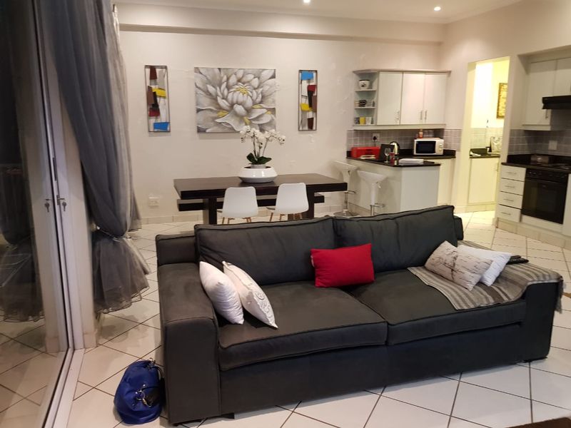 Open-plan living and dining area featuring tiled floors, a modern kitchen with granite countertops, built-in appliances, and access to a patio through sliding doors.