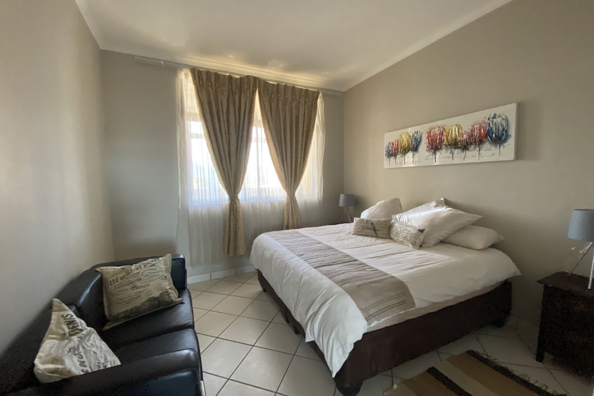 A well-lit bedroom featuring neutral wall tones and tiled flooring, offering a comfortable and functional living space.