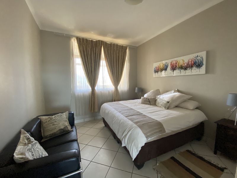 A well-lit bedroom featuring neutral wall tones and tiled flooring, offering a comfortable and functional living space.