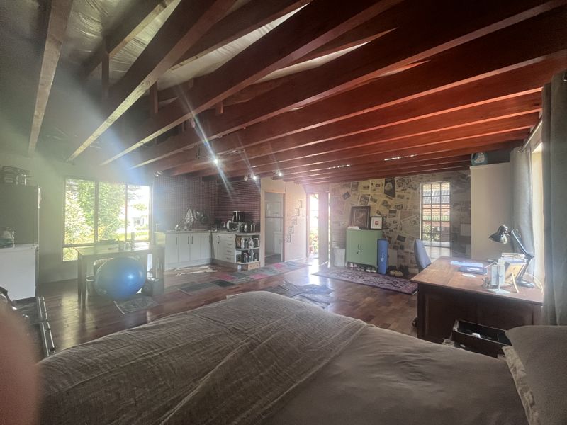 Spacious open-plan living area featuring exposed timber ceiling beams, hardwood flooring, and a functional kitchen layout with integrated cabinetry.