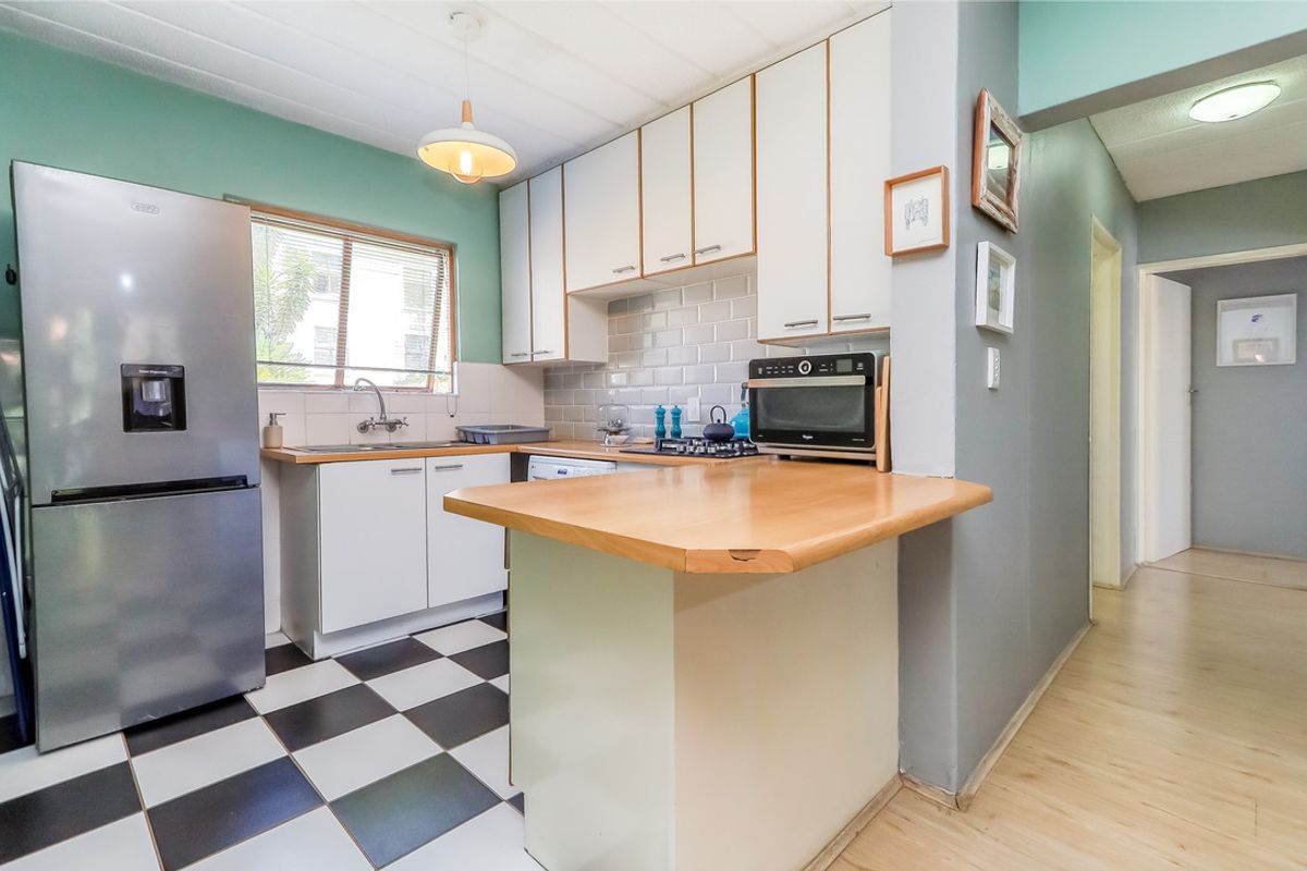 A functional kitchen featuring white cabinetry, subway tile backsplash, a breakfast bar, and a classic black and white checkered floor.