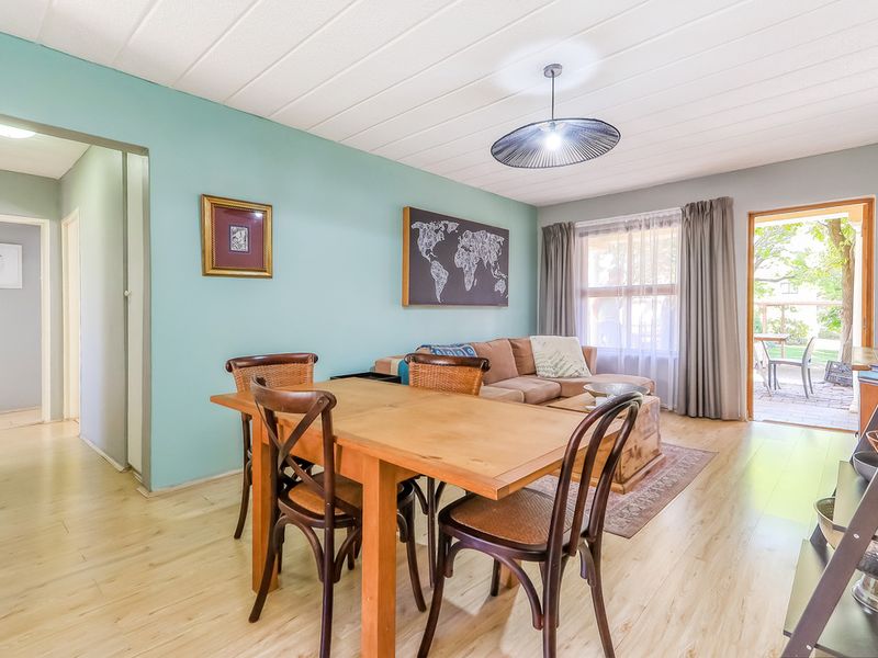 Open plan living and dining area featuring light laminate flooring, a textured ceiling, and direct access to an outdoor patio space.