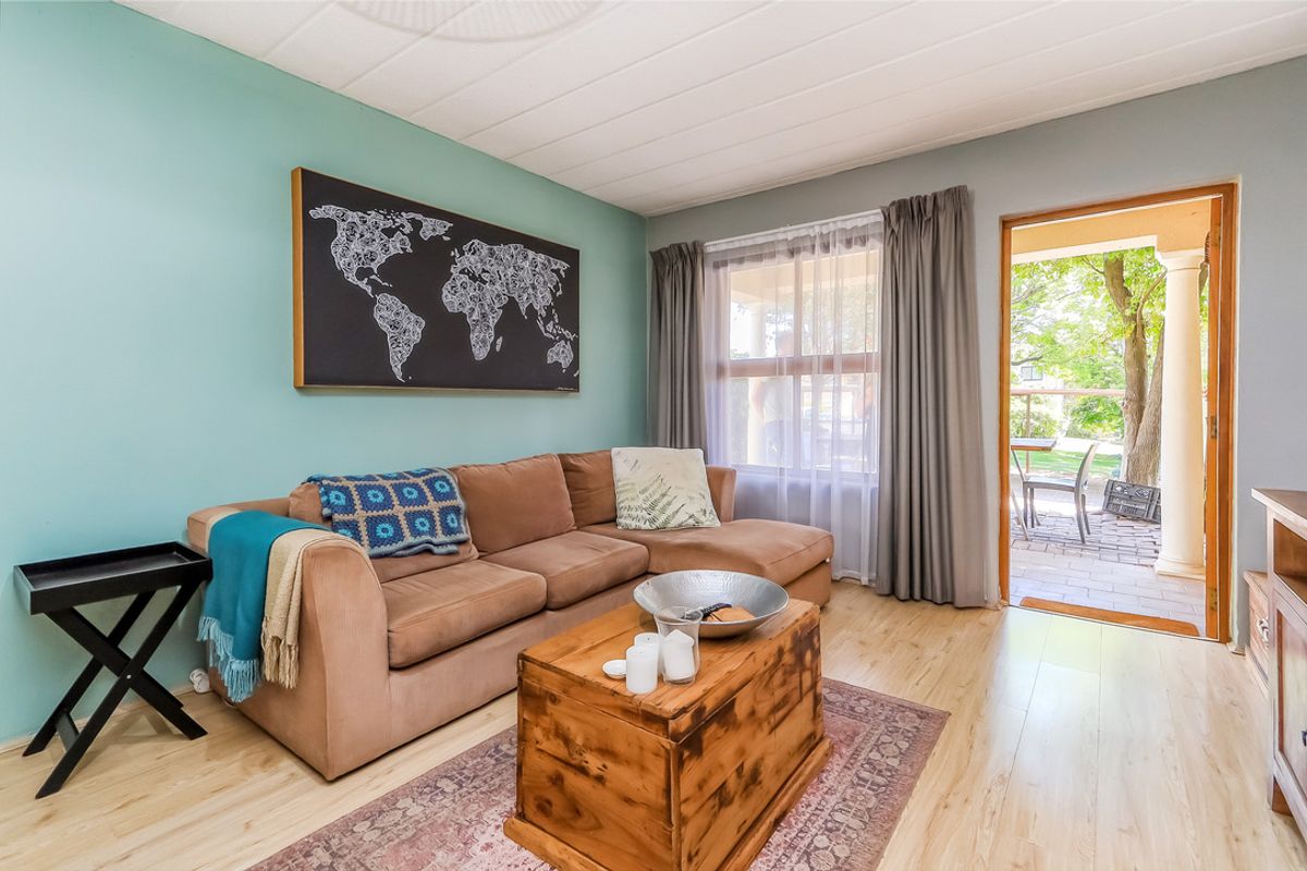A bright living room featuring light laminate flooring and direct access to an outdoor patio area through a sliding door.