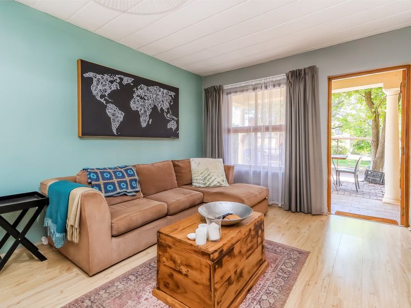 A bright living room featuring light laminate flooring and direct access to an outdoor patio area through a sliding door.