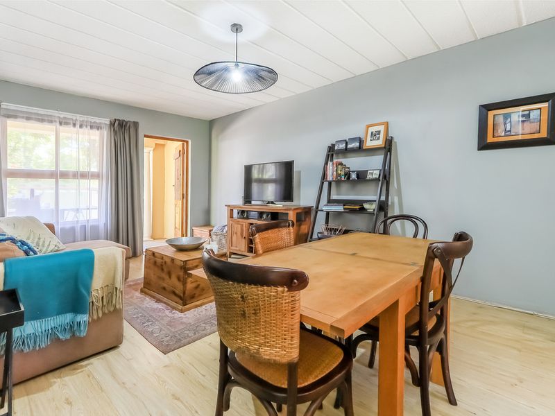 Open plan living and dining area featuring light laminate flooring and a suspended ceiling with direct access to an outdoor space.