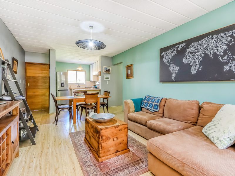 Open-plan living and dining area featuring laminate flooring and a functional kitchen space with built-in cabinetry.