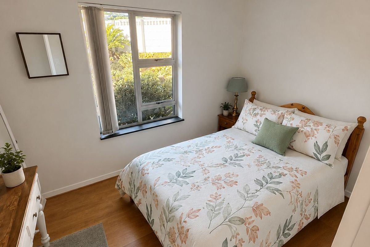 A well-maintained bedroom featuring laminate flooring, neutral walls, and a window providing natural light.