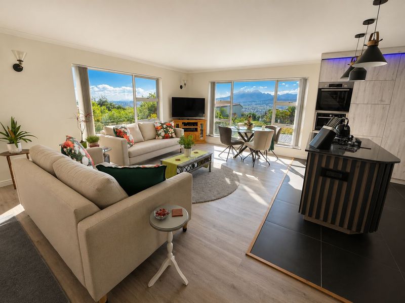Bright open-plan living and kitchen area featuring modern finishes, a central island, and expansive windows showcasing scenic mountain views.