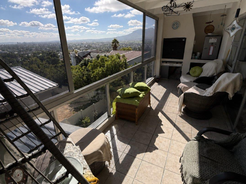 Enclosed balcony featuring tiled flooring, exposed beam ceiling, and expansive glass windows offering panoramic mountain and city views.