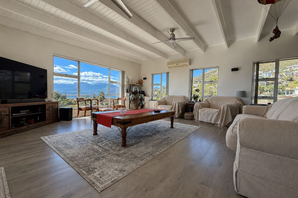 Spacious living room featuring exposed beam ceilings, ceiling fans, and large windows offering panoramic mountain and landscape views.