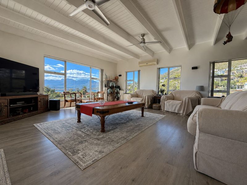 Spacious living room featuring exposed beam ceilings, ceiling fans, and large windows offering panoramic mountain and landscape views.