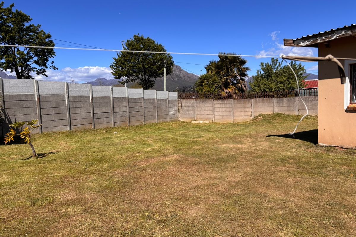 A spacious rear garden featuring a precast concrete boundary wall and mountain views, offering potential for landscaping and outdoor improvement.