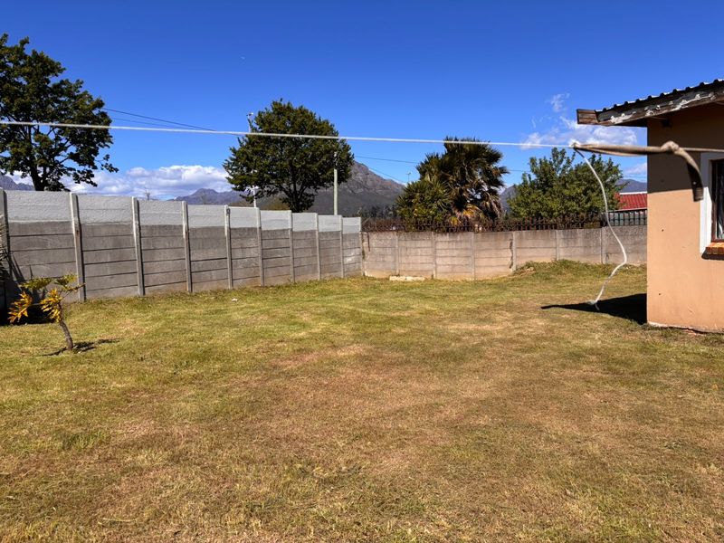 A spacious rear garden featuring a precast concrete boundary wall and mountain views, offering potential for landscaping and outdoor improvement.
