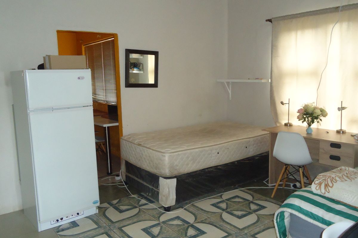 A bedroom featuring tiled flooring and built-in shelving, offering a functional space that could benefit from cosmetic updates and modern finishes.