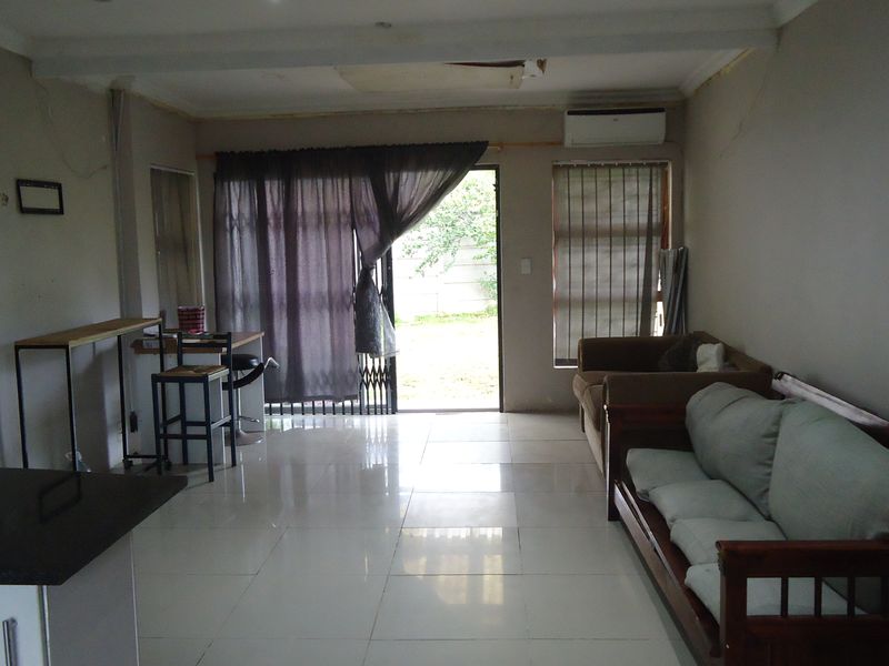 Open-plan living area featuring tiled floors, a split-system air conditioner, and direct access to the rear garden through a sliding door.