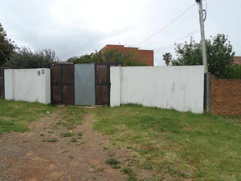 Front view of the property featuring a boundary wall and driveway gate entrance.