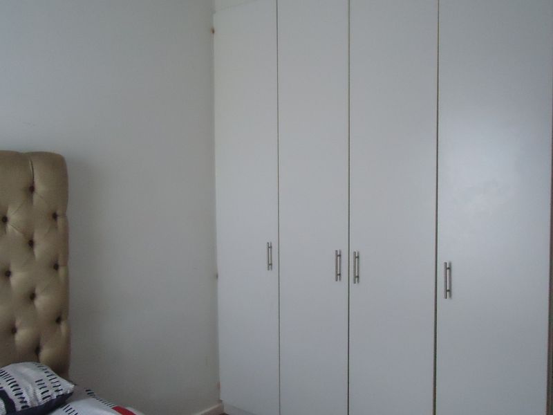 A bedroom featuring a large, white built-in wardrobe with modern handles, providing ample storage space.