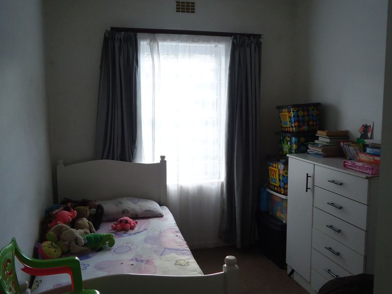 A standard bedroom featuring a window with curtains and a ventilation grille, providing a functional space for rest.