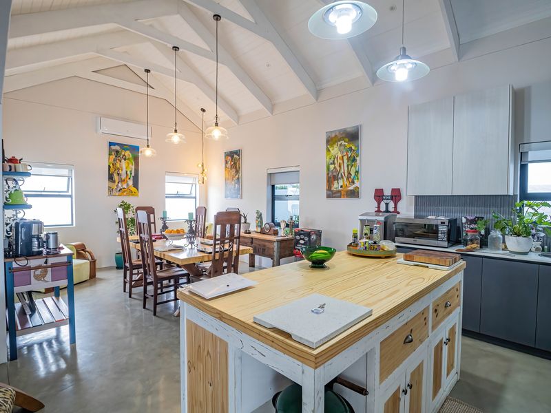 Spacious open-plan living and dining area featuring a vaulted ceiling with exposed rafters, a central kitchen island, and modern cabinetry.