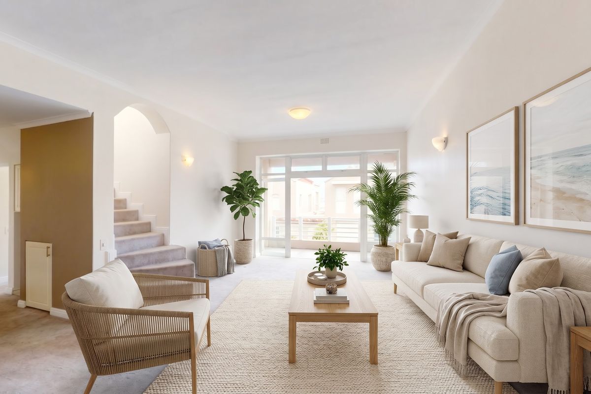 A bright and spacious living room featuring neutral carpeting, an elegant archway leading to a staircase, and large sliding doors providing natural light.
