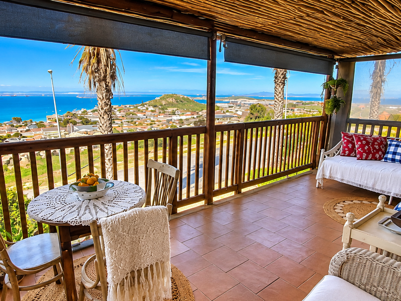 Covered balcony featuring a timber pole roof, tiled flooring, and a timber balustrade, offering expansive coastal and neighbourhood views.