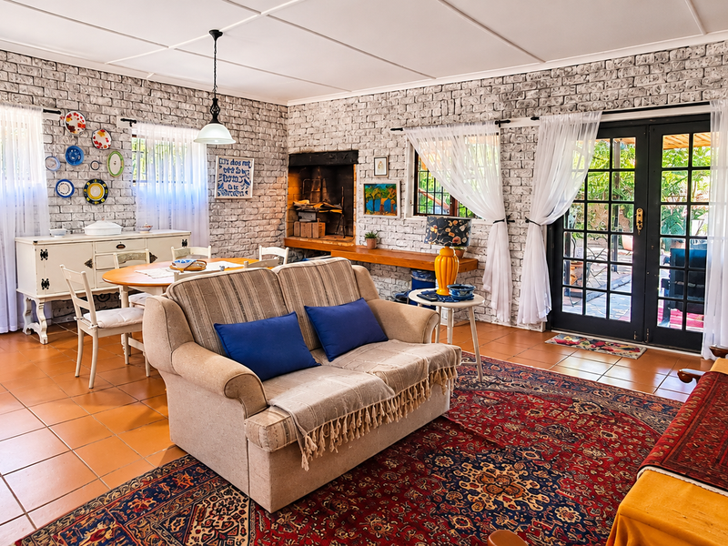 Spacious open-plan living and dining area featuring rustic exposed brick walls, tiled flooring, a built-in fireplace, and direct access to the outdoor patio.