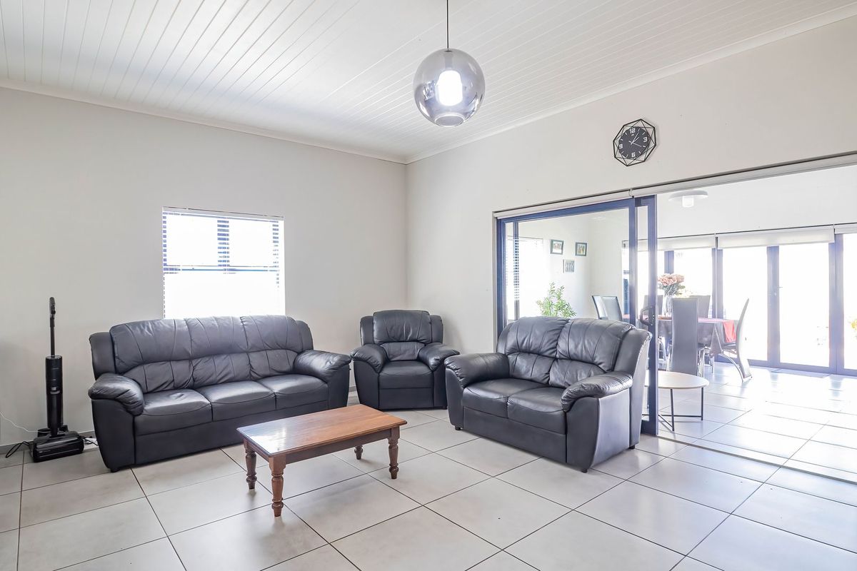 Spacious living area featuring neutral tiled flooring, a classic tongue and groove ceiling, and large sliding glass doors providing access to the adjacent room.