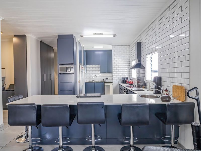 Modern kitchen featuring a large island with quartz countertops, subway tile backsplash, integrated cabinetry, and high-quality built-in appliances.