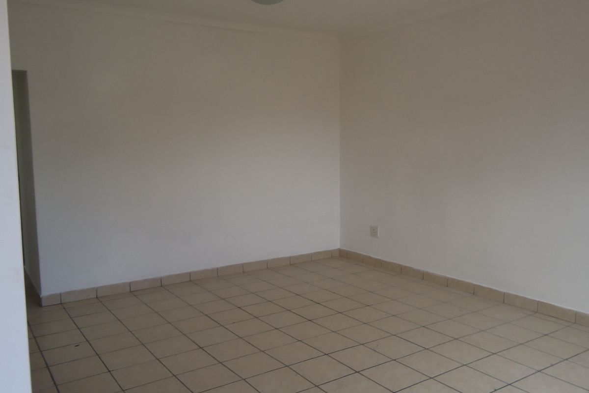 An empty, neutral-toned living area featuring tiled flooring and simple finishes, providing a blank canvas for interior design.