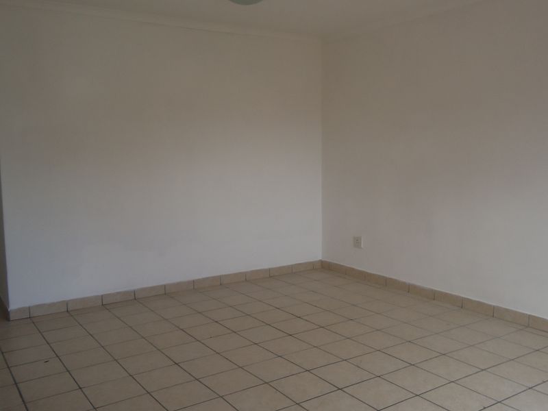 An empty, neutral-toned living area featuring tiled flooring and simple finishes, providing a blank canvas for interior design.