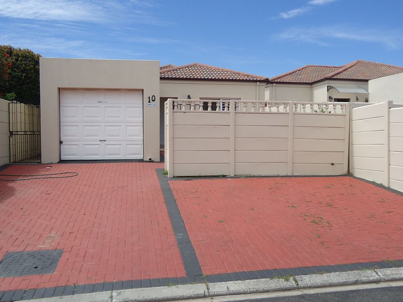 Front exterior view of the property featuring a single garage, paved driveway, and secure boundary walling.