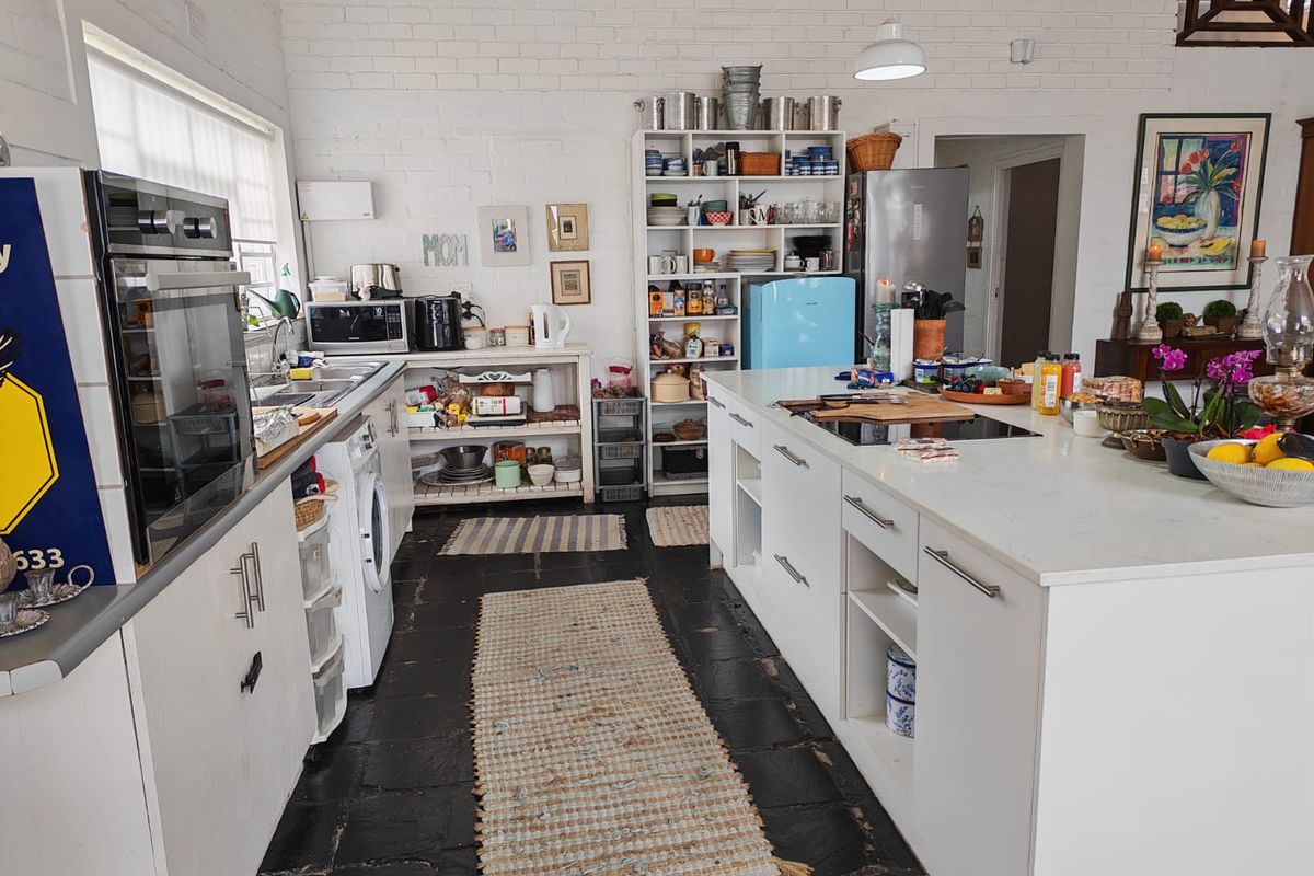 A spacious kitchen featuring a central island with a built-in cooktop, white cabinetry, and exposed brick walls, offering a functional and bright cooking space.