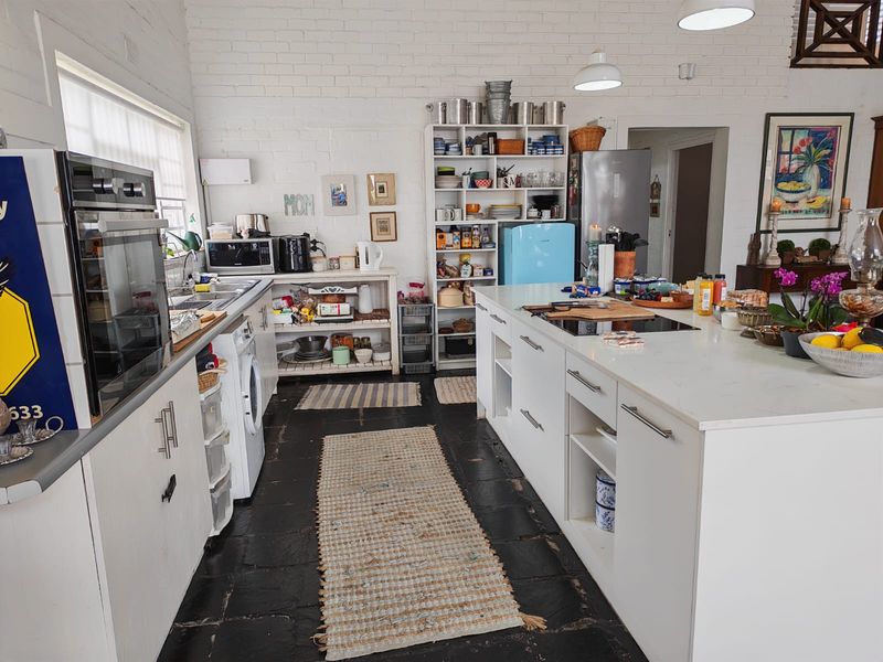A spacious kitchen featuring a central island with a built-in cooktop, white cabinetry, and exposed brick walls, offering a functional and bright cooking space.