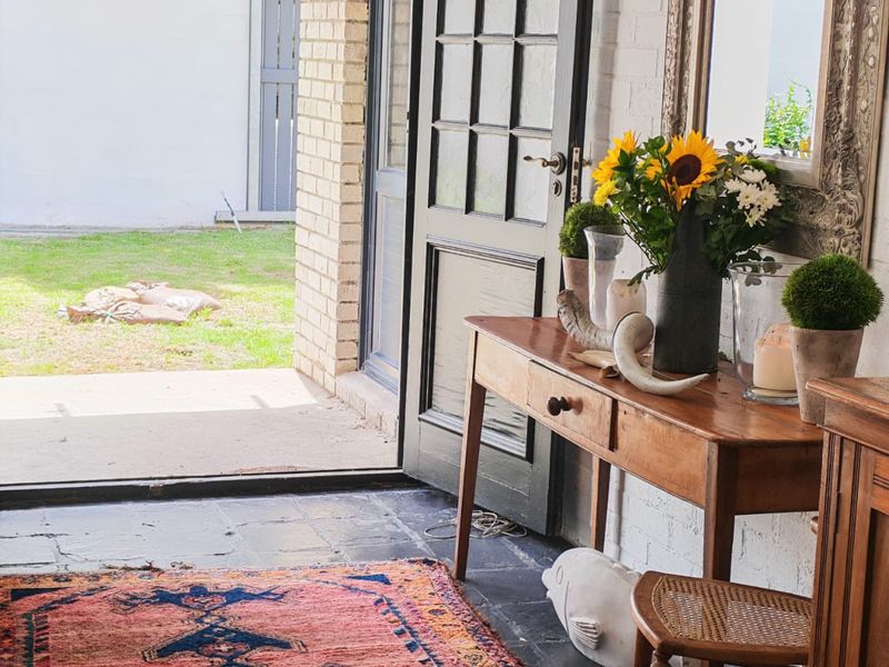 An inviting entryway featuring slate flooring and a classic paneled door opening directly onto a private rear garden area.