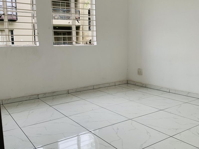 An empty bedroom featuring white marble-look tiled flooring and windows fitted with security bars.