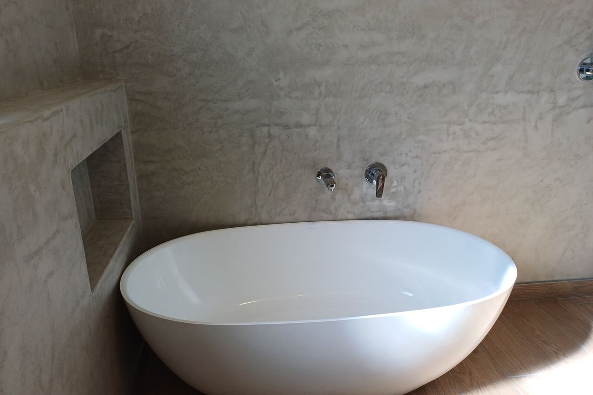 Modern bathroom featuring a sleek freestanding bathtub with wall-mounted chrome fixtures and a built-in recessed wall niche for storage.